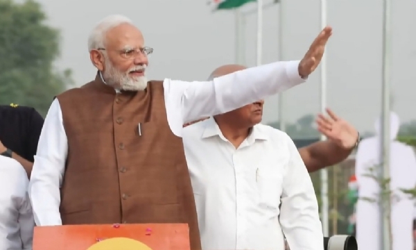 Prime Minister Narendra Modi waves to cheering crowds during a roadshow in Banaskantha, Gujarat on Friday