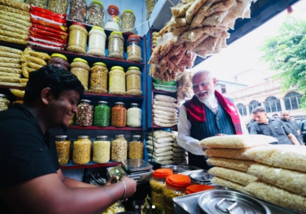 PM Modi holding a cup of jhalmuri amid an enthusiastic crowd at the Jhargram stall, embodying his approachable style during the campaign.