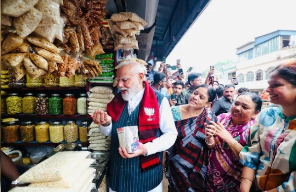 PM Modi holding a cup of jhalmuri amid an enthusiastic crowd at the Jhargram stall, embodying his approachable style during the campaign.