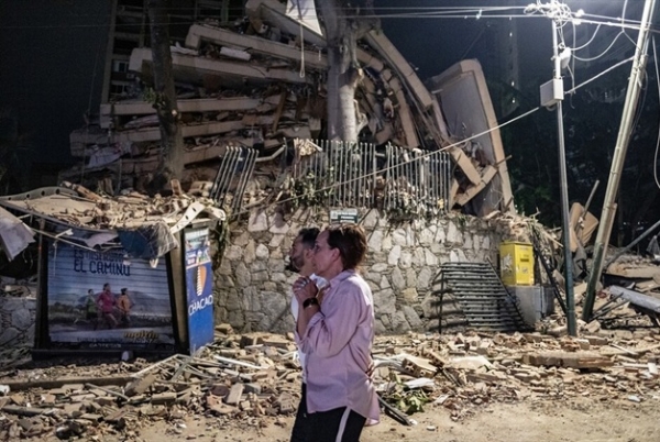 A local woman walks past a building that collapsed like a house of cards following the devastating earthquake in Caracas, the capital of Venezuela.
