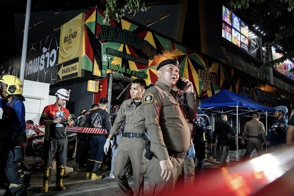 Police officers and firefighters deployed at the scene following a fire at a pub in Bangkok.