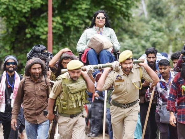 Jammu and Kashmir Police personnel carry a woman pilgrim in a makeshift chair along the Pahalgam route during the annual Amarnath Yatra