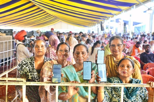 Women beneficiaries showing mobile phones after receiving the financial assistance.