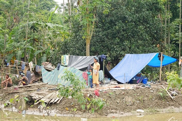 Photo Caption: A flood-affected family waits for assistance under a tarpaulin shelter in Assam.